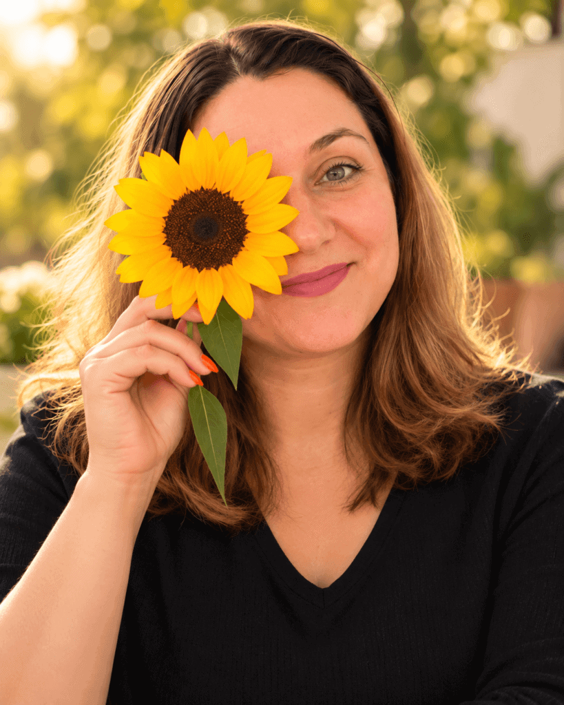 Silvia Ecobici zâmbind cu o floarea-soarelui